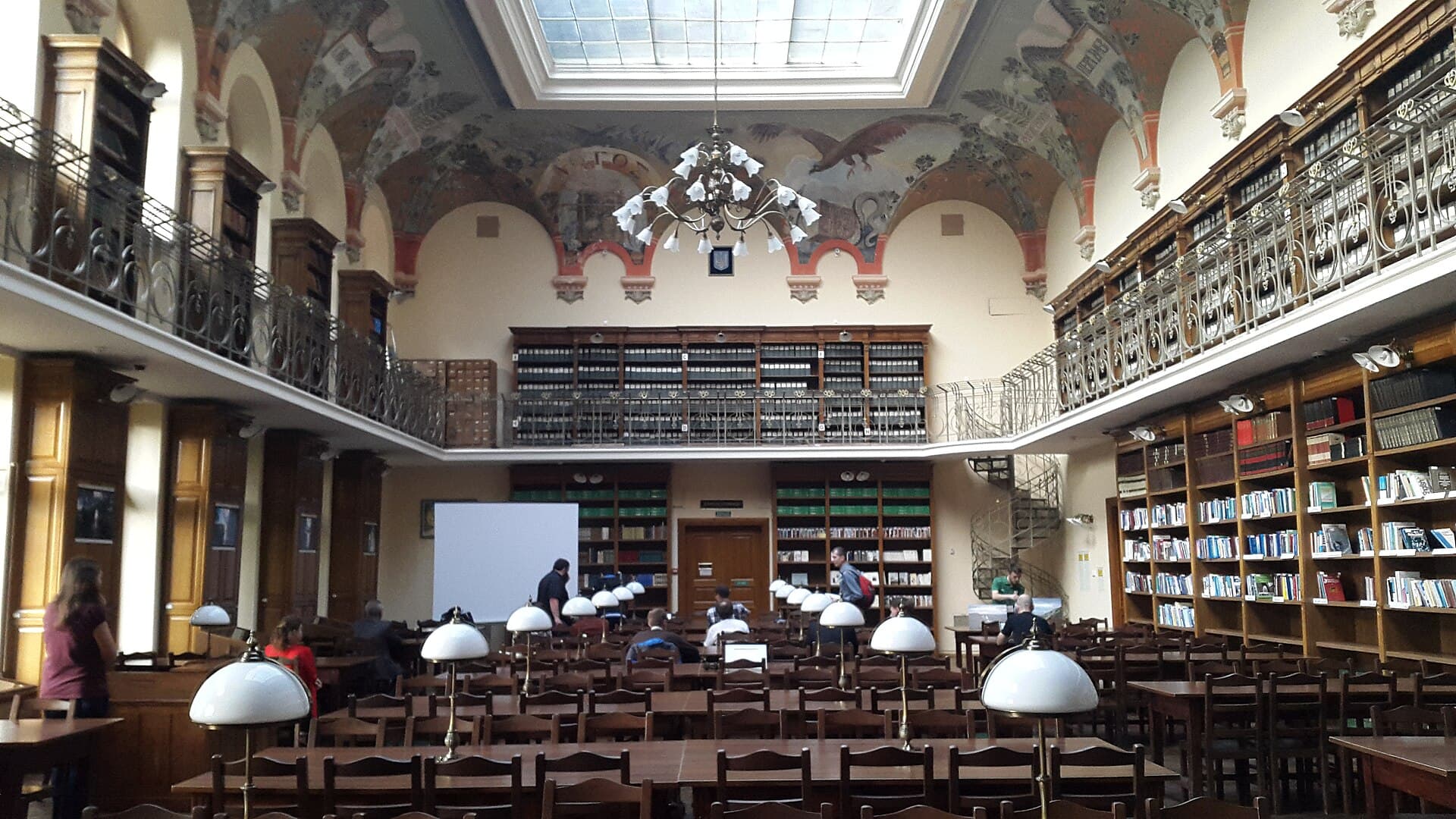 The main reading hall of the Ivan Franko National University Scientific Library in Lviv — painted vaulted ceilings, gallery balconies of books, and readers at work under a skylight